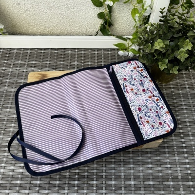 Estojo de tecido com padrões riscado e floral, com fecho e fita azul