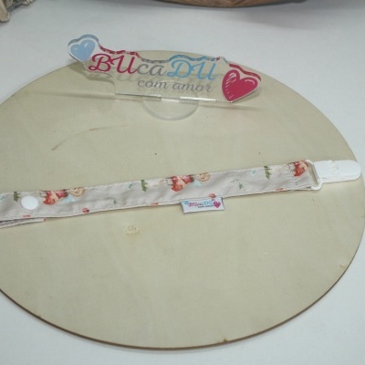 Presilha para chupeta tecido bege com padrão colorido numa placa redonda de madeira clara