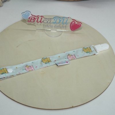 Pulseira para chupeta com padrão de corujas em tecido sobre suporte redondo de madeira