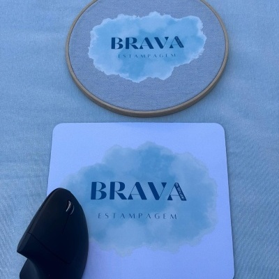 Tapete de rato branco com padrão azul e texto BRAVA ESTAMPAGEM e rato preto ao lado, bastidor de madeira com tecido e papel com padrão e texto iguais.