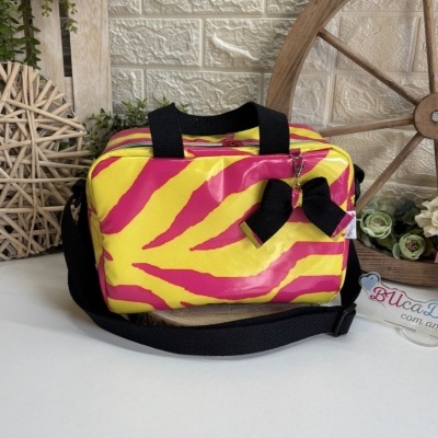 Bolsa em padrão animal amarelo e rosa com laço preto junto a flores e decoração rústica