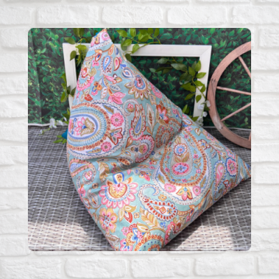 Puff com padrão floral em tons pastel num ambiente com moldura branca e roda de madeira