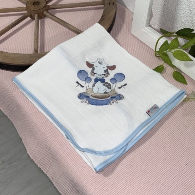 Toalha branca de criança com bordado de vaca e balões azuis sobre tecido rosa