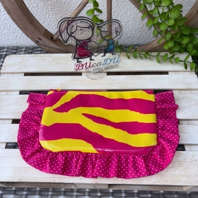 Nécessaire amarelo e rosa com renda rosa de bolinhas em fundo de madeira clara com decoração de roda de madeira e plantas