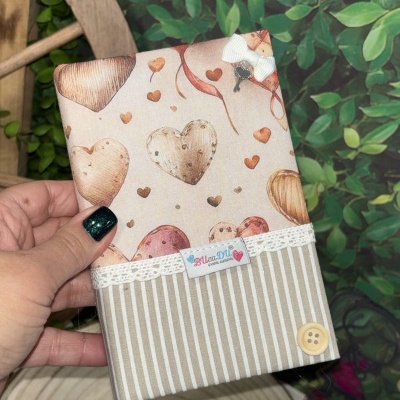 Capa em tecido com padrão de corações e detalhes em renda, botão e laço