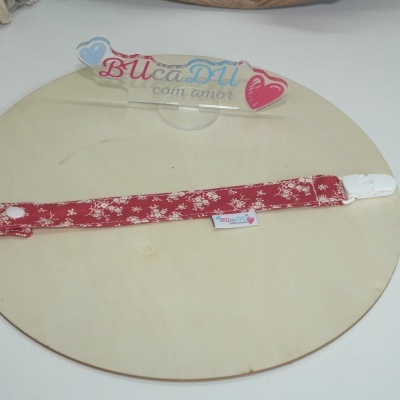 Pulseira ou prendedor em tecido vermelho com padrão floral branco e fecho em plástico branco.