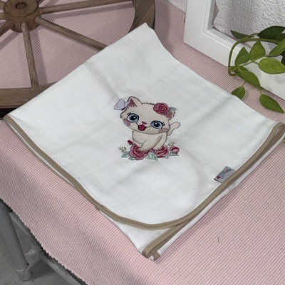 Toalha branca com bordado de gato e flores sobre tecido rosa
