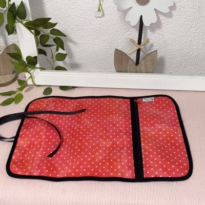 Estojo vermelho com padrão de bolinhas brancas e fecho de correr preto aberto