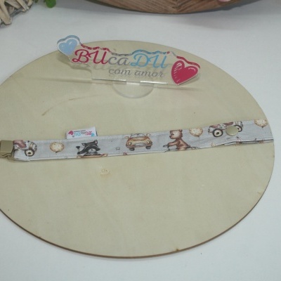 Laço de tecido cinzento com padrão de carros e ursos sobre placa redonda de madeira clara