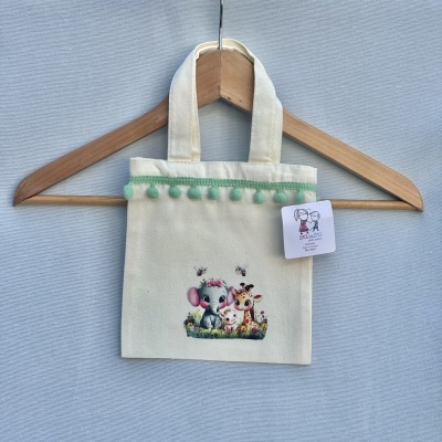 Mala pequena bege com pompons verdes e desenho de animais sorridentes