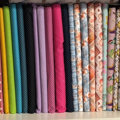 Tecidos dobrados com diferentes padrões e cores numa prateleira