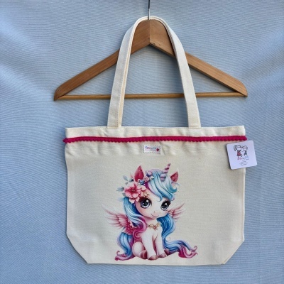 Mala de tecido cru com estampa de unicórnio colorido e pompons cor-de-rosa