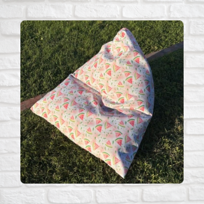 Pufe triangular com padrão de melancia sobre relva