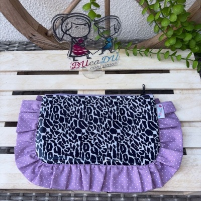 Bolsa de tecido com padrão animal print e risca lilás, etiqueta BUcaDU com amor, em suporte acrílico, fundo madeira e plantas