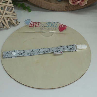 Correia para chupeta cinza com padrão de ursos e botão branco sobre placa de madeira redonda.