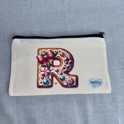 Estojo branco com fecho preto e decoração de letra R estilo biscoito natalício