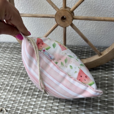 Bolsa com padrão de melancia e riscas cor de rosa segurada junto a roda de madeira