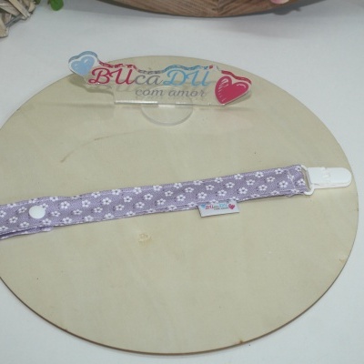 Prendedor de chupeta lilás com pegadas brancas e etiqueta BUcaDU com amor