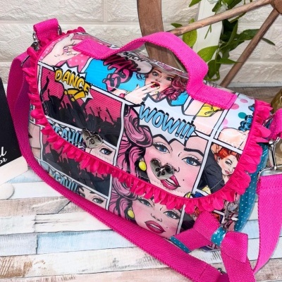 Mala tiracolo com padrão banda desenhada e alça rosa ajustável.