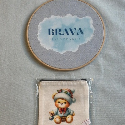 Guarda bordado com estampa BRAVA e estojo branco com imagem de ursinho com gorro de inverno e laço vermelho.