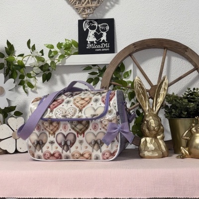 Bolsa colorida com padrão de corações e laço lilás sobre mesa rosa com decoração