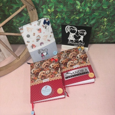 Três capas de tecido decoradas para livros com botões e padrões variados, duas com tema de cães e uma com tema de costura.