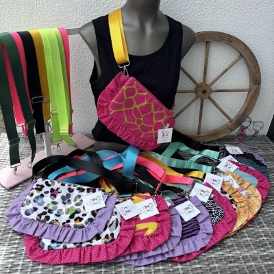 Bolsas coloridas com estampas e babados sobre mesa com manequim e roda de madeira