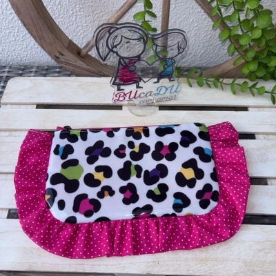 Necessaire colorida sobre mesa de madeira com decoração de roda em madeira e planta verde