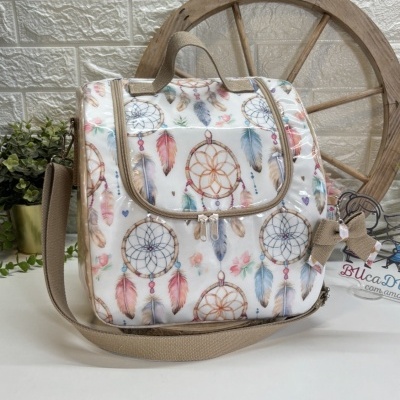 Bolsa quadrada com padrão de atrapas sonhos e penas em cores suaves e acabamento em vinil transparente.