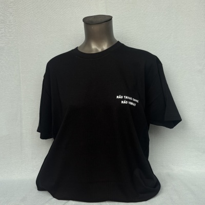T-shirt preta com texto branco NÃO TAVAS CAPAZ NÃO VINHAS numa montra.