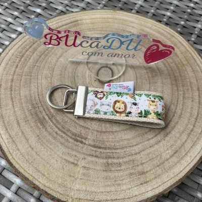 Chaveiro tecido com padrão de animais sobre placa de madeira redonda