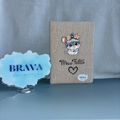 Capa bege com rato cartoon e texto Mau Feitio, placa acrílica azul com BRAVA ESTAMPAGEM