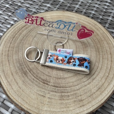 Chaveiro de tecido com estampa de cães em fundo azul sobre placa de madeira