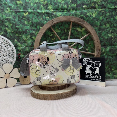 Bolsa infantil com padrão da Minnie Mouse e laço cinza sobre suporte de madeira