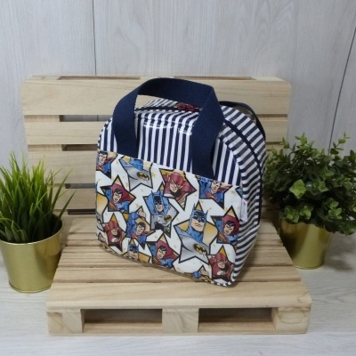 Bolsa térmica com riscas azuis e brancas e personagens de banda desenhada, entre plantas e figura amarela