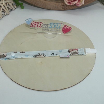 Fita para chupeta azul claro com padrão de vacas, notas musicais e corações, etiqueta e fecho branco