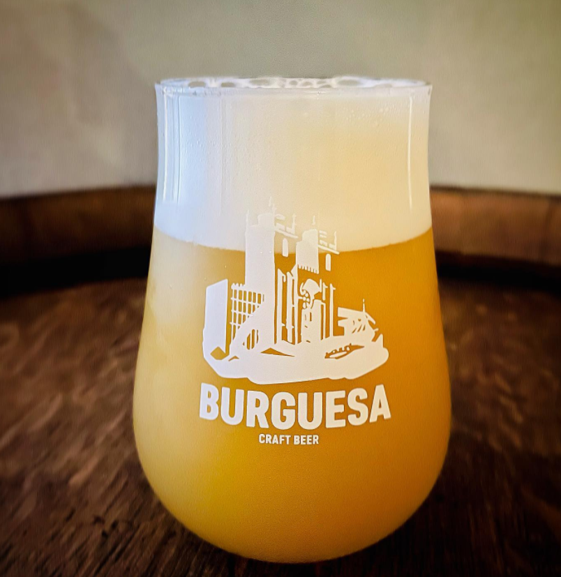 Copo de vidro com cerveja artesanal BurGUESA e espuma branca