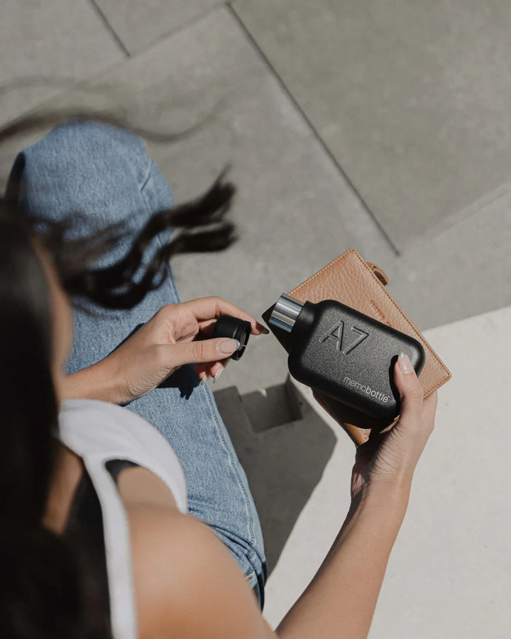 A7 memobottle Stainless Steel - BLACK Frasco preto A7 memobottle nas mãos de uma pessoa sentada com jeans azuis