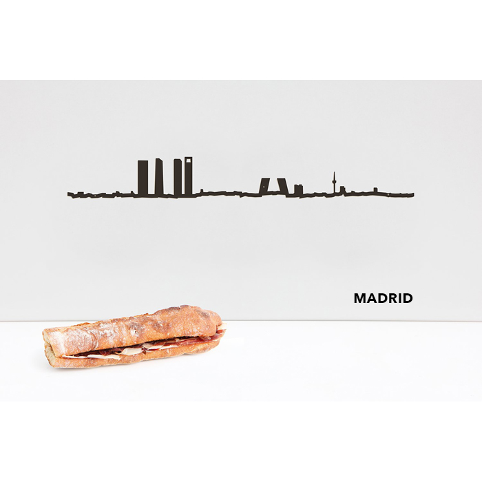 theLine® Small 50 cm - Black _ Madrid Silhueta preta de Madrid decorativa na parede branca com pão tipo baguete em superfície branca