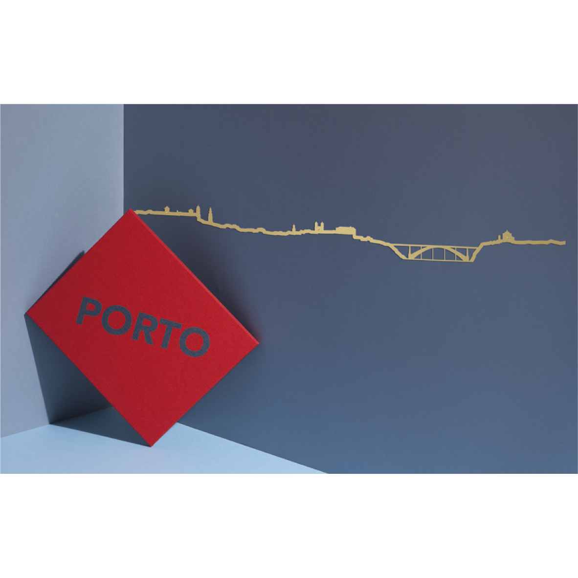 theLine® Small 50 cm - Black _ Porto Placa vermelha com a palavra 'PORTO' e linha dourada com panorama da cidade sob fundo azul.