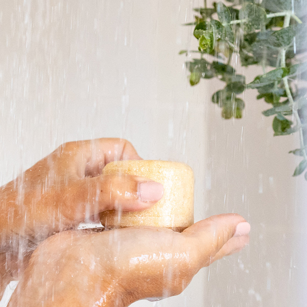 Champô Sólido NAUA Couro Cabeludo Sensível Mãos segurando sabonete sólido sob água