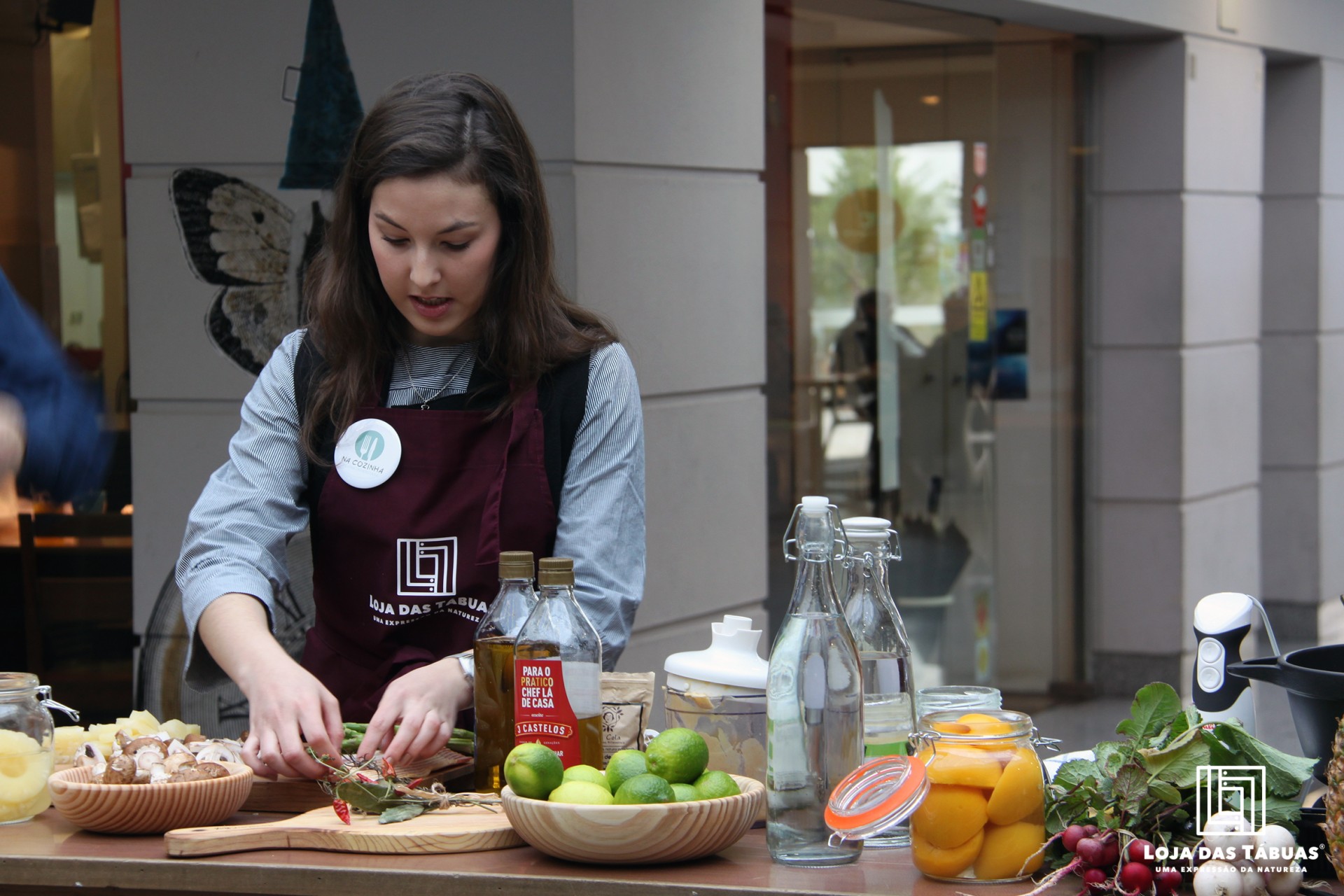 Mulher com avental preparando comida numa mesa exterior com frutas e vegetais