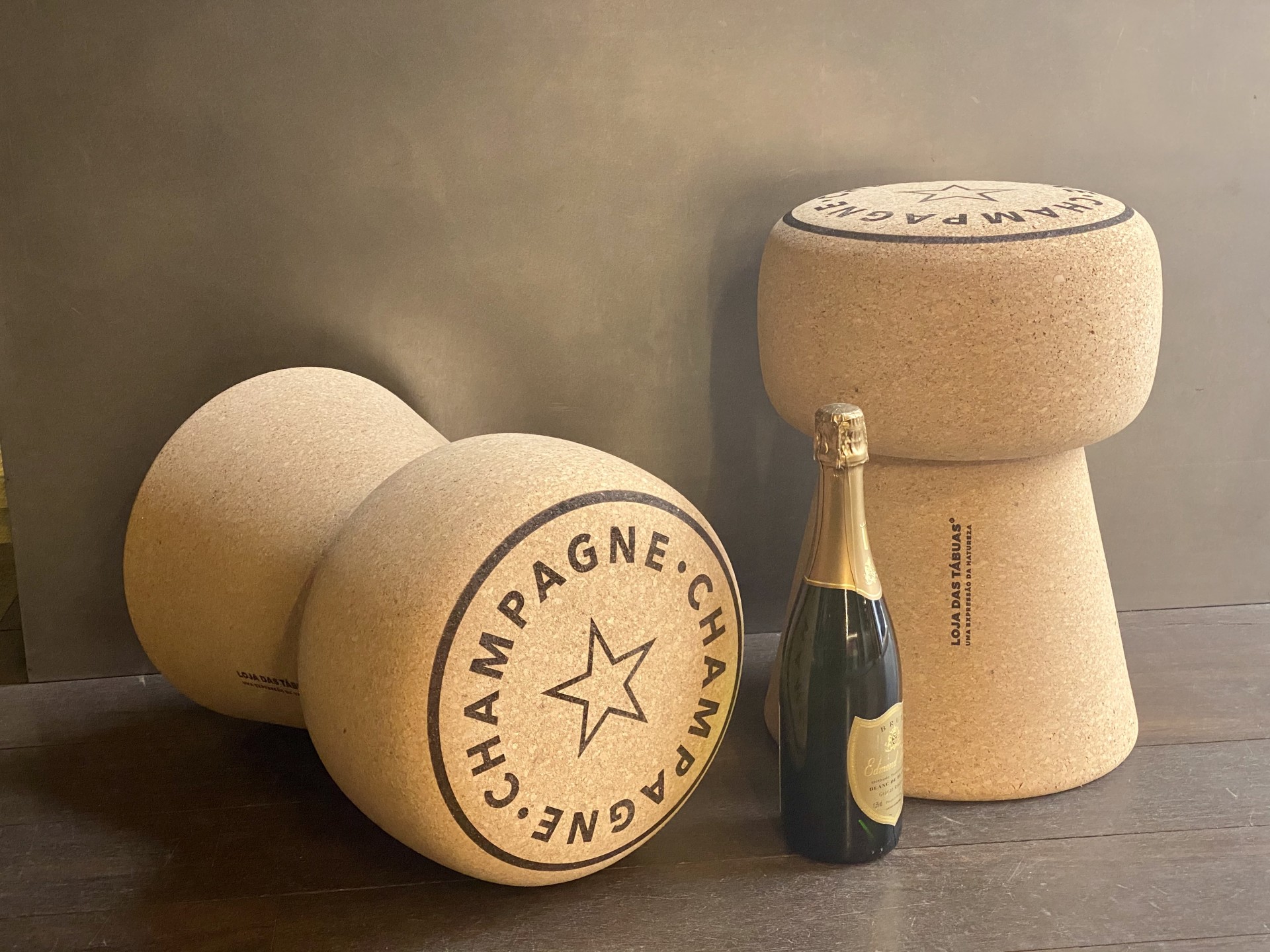 Banco em Cortiça Maciça em Formato de Rolha de Champanhe - Inscrição "Champagne" no topo Bancos de cortiça em forma de rolha de champanhe com garrafa de champanhe ao centro