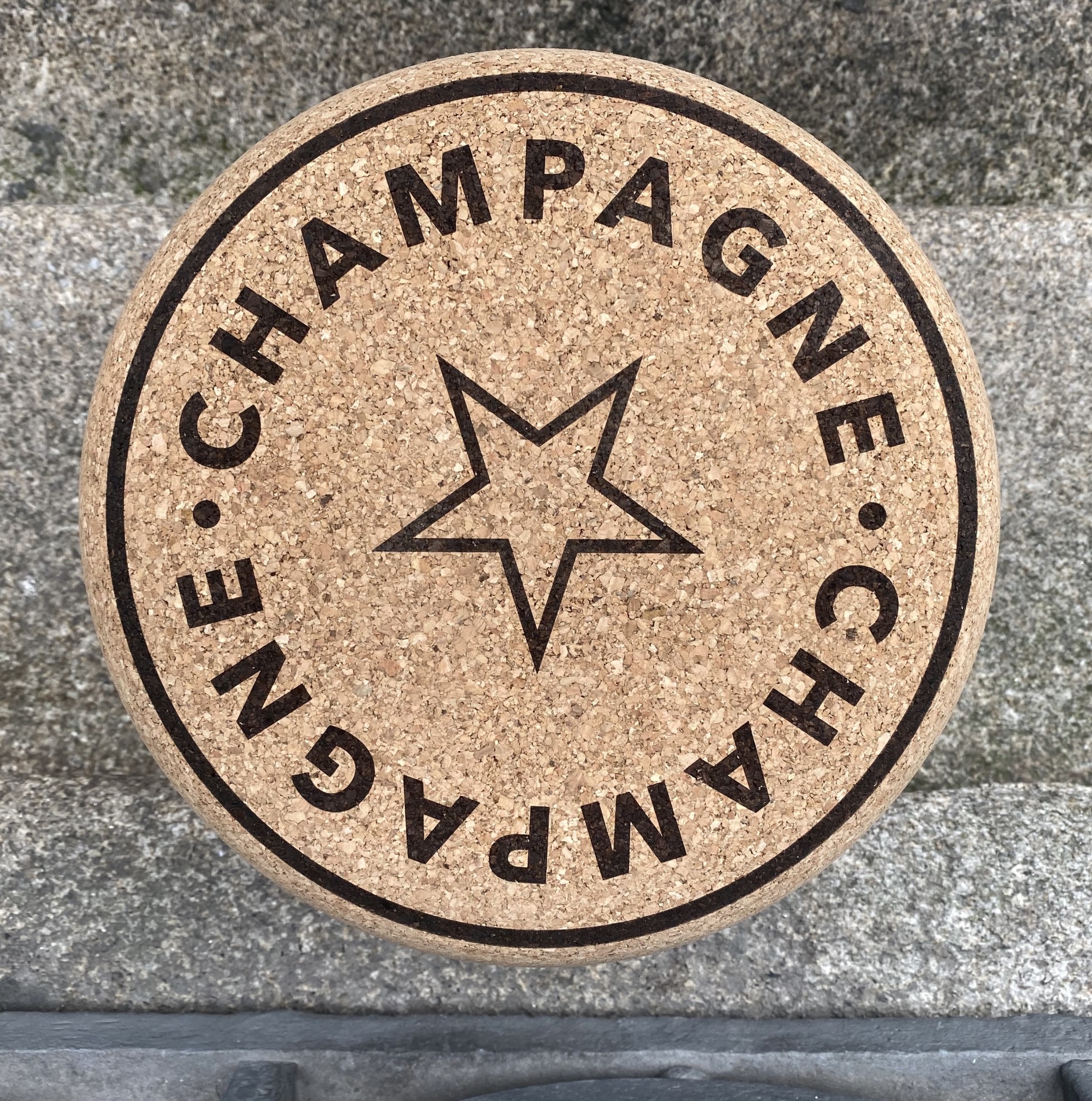 Banco em Cortiça Maciça em Formato de Rolha de Champanhe - Inscrição "Champagne" no topo Tampão de cortiça redondo com texto CHAMPAGNE e estrela preta no centro