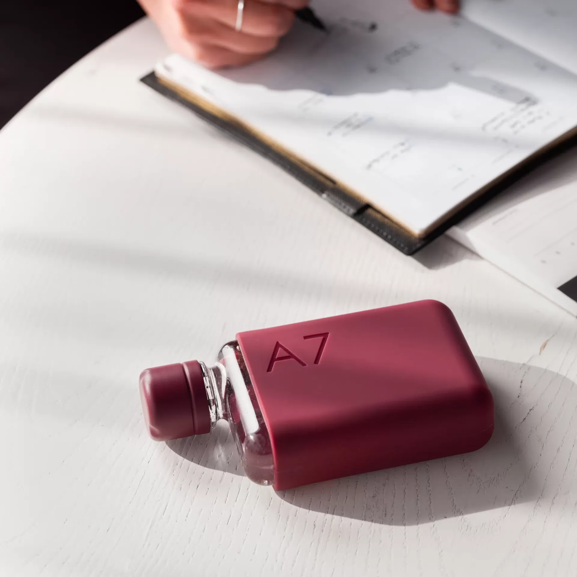 A7 Silicone Sleeve - Wild Plum Garrafa de água com capa de silicone cor-de-rosa escuro com gravação A7 sobre mesa branca