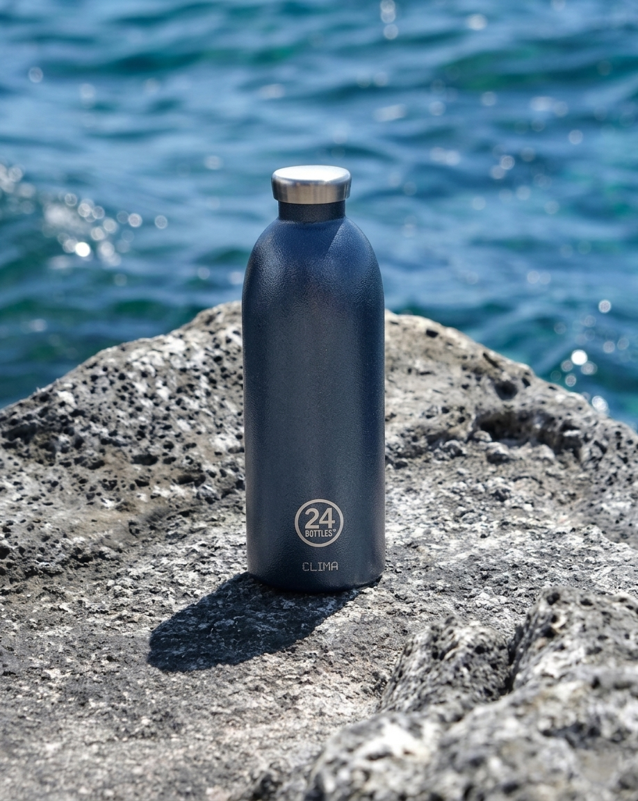 Clima Bottle - Deep Blue 850ml Garrafa térmica azul escura com tampa de aço inoxidável em cima de rocha junto ao mar