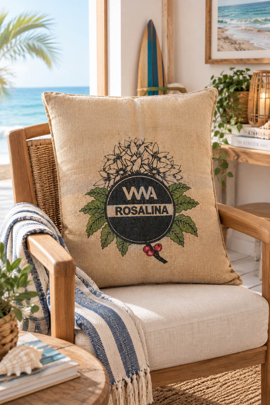 Almofada em Serapilheira Reciclada - 80X60CM Almofada decorativa bege com estampa do logotipo VVA Rosalina numa cadeira de madeira com almofada creme e manta azul e branca