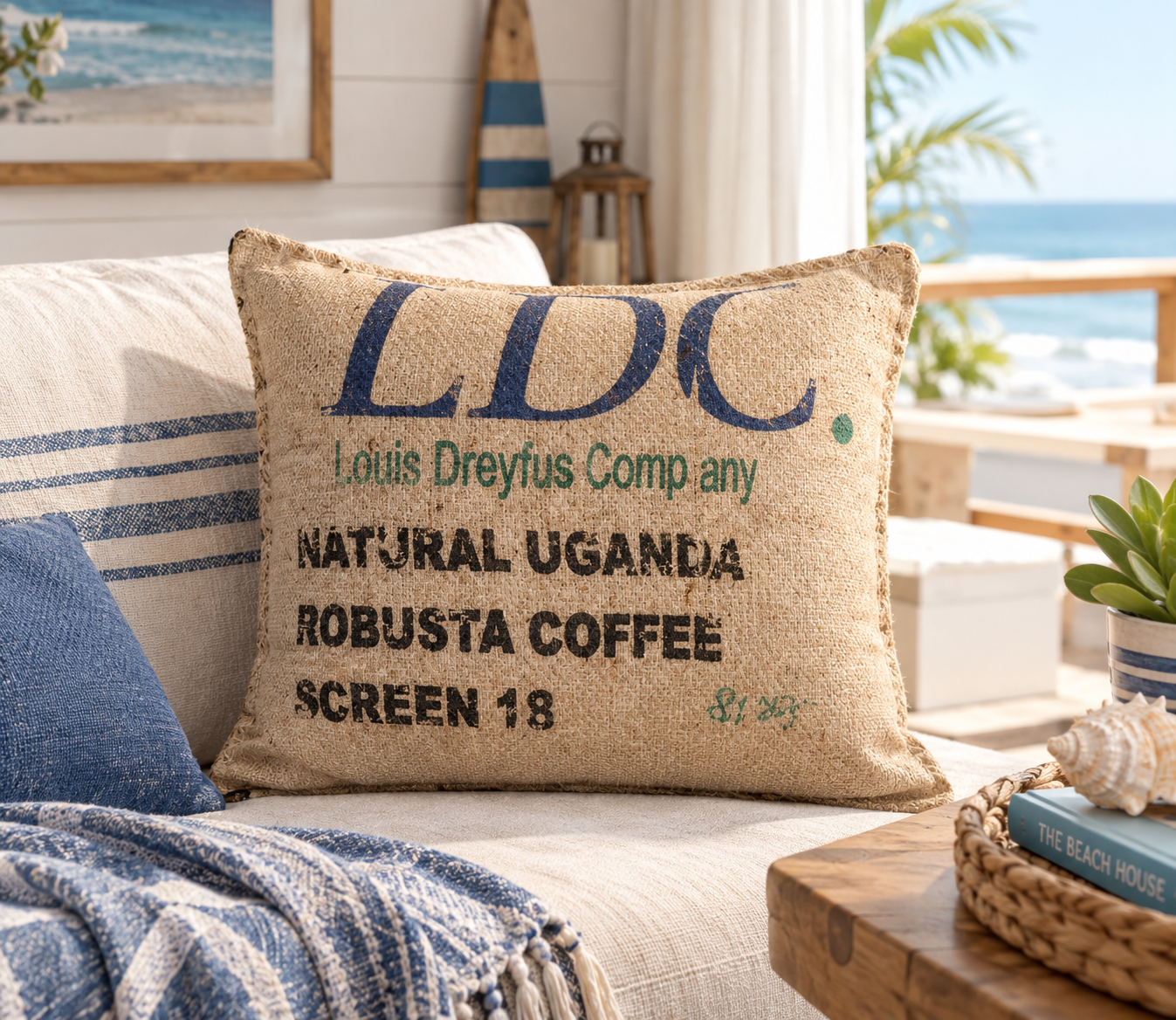 Almofada em Serapilheira Reciclada - 60X50CM Almofada rústica castanha com texto em azul e preto em cama ou sofá com vista para o mar