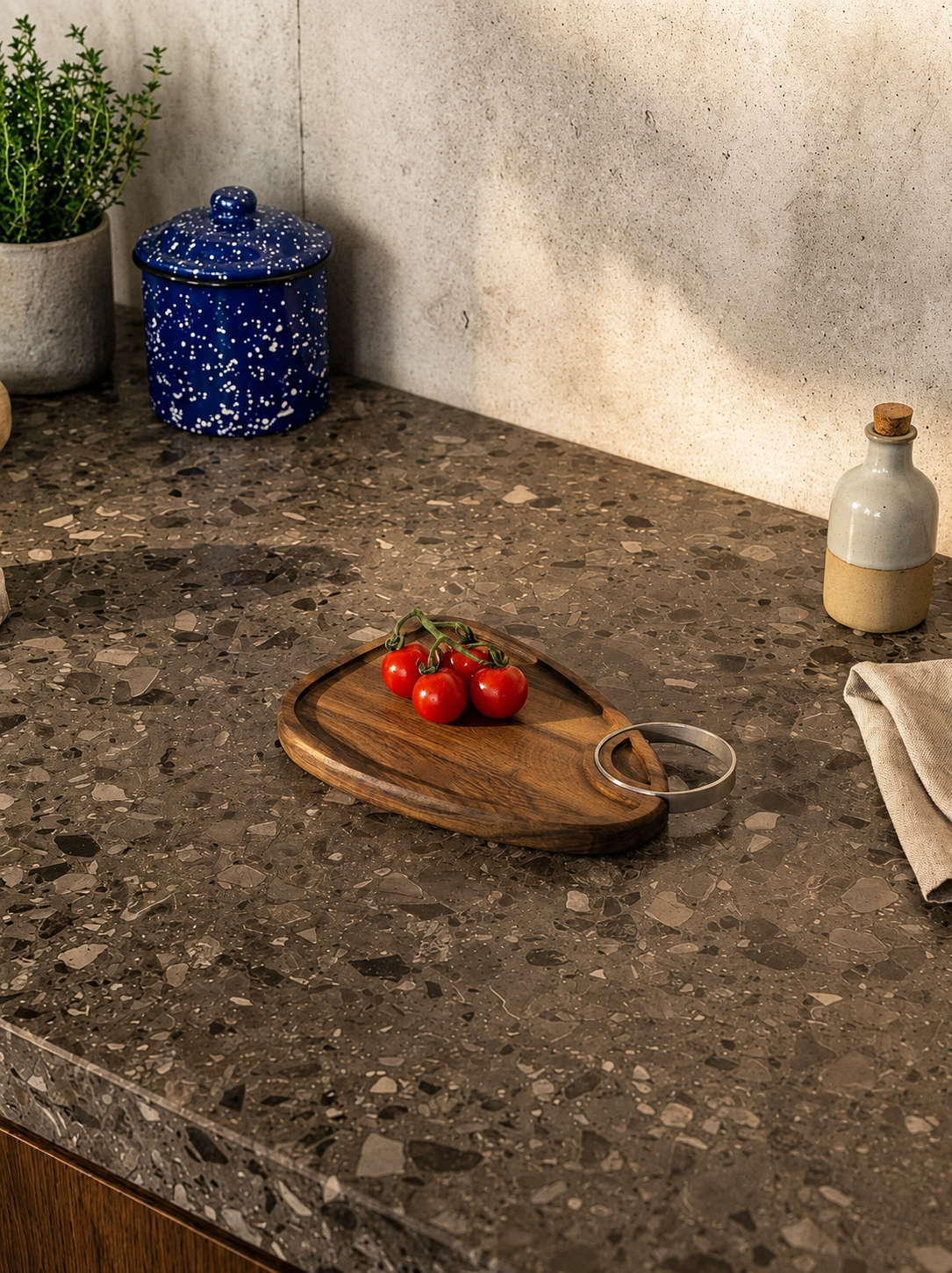BIRD WALNUT CUTTING BOARD - S Bancada de cozinha em pedra castanha com tábua de madeira, tomate-cereja, frascos cerâmicos e vaso com planta