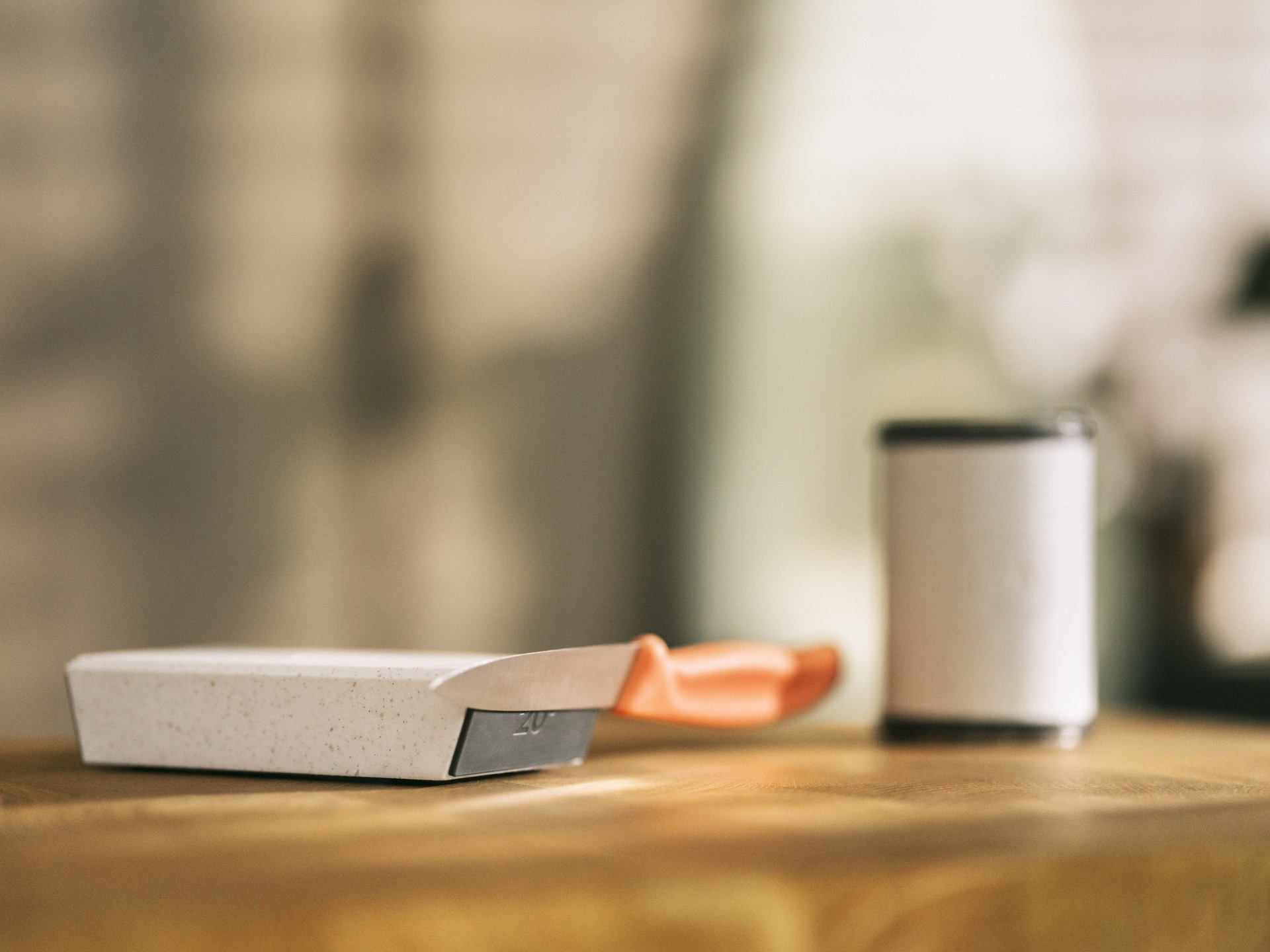 HORL 3 Sharpener Cruise – Tecnologia Avançada para Afiação de Facas com Discos de Diamante e Aço, Ângulos de 15º e 20° Faca de cozinha com cabo laranja e tábua de corte branca numa superfície de madeira